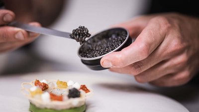 Mani che aggiungono caviale a un antipasto gourmet delicato