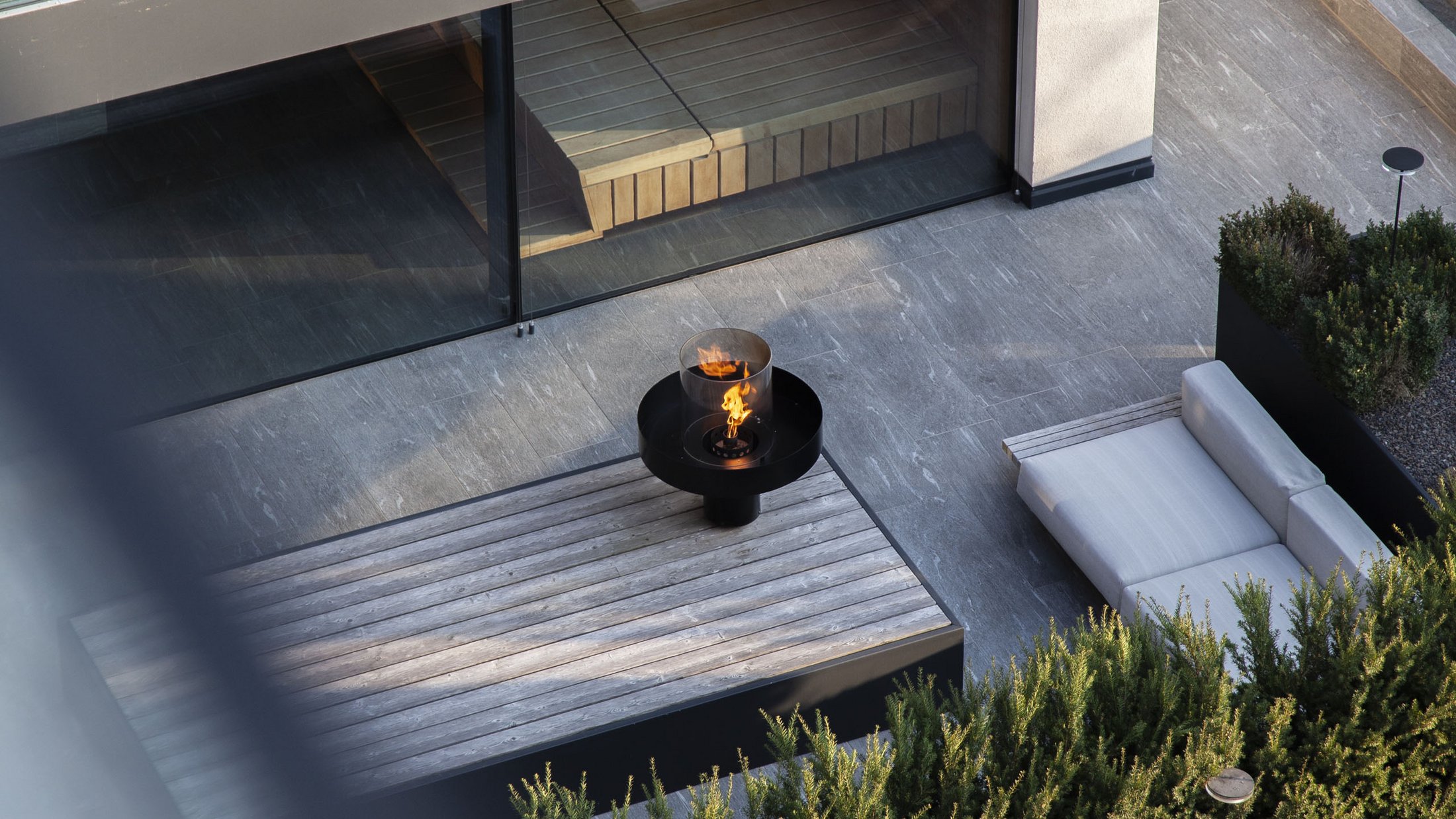 Modern outdoor area with tables, chairs, sofa, and fire table
