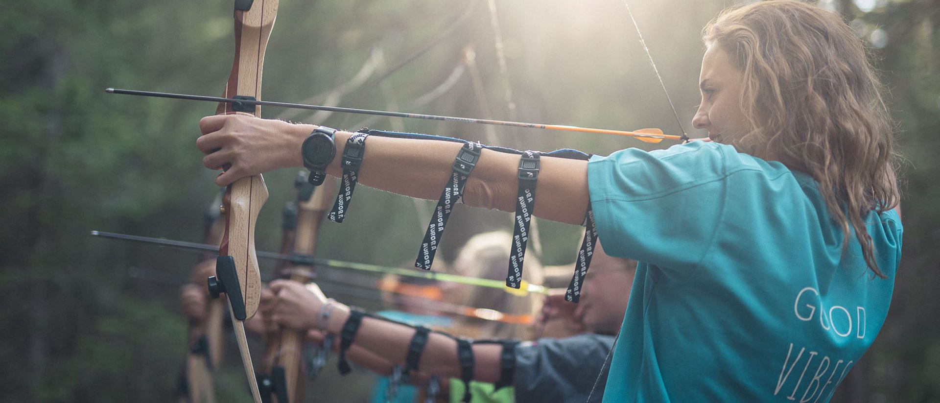 Personen schießen mit Pfeil und Bogen im Wald bei Sonnenlicht