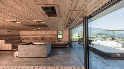 Area sauna moderna con rivestimento in legno e finestra panoramica con vista sulle montagne