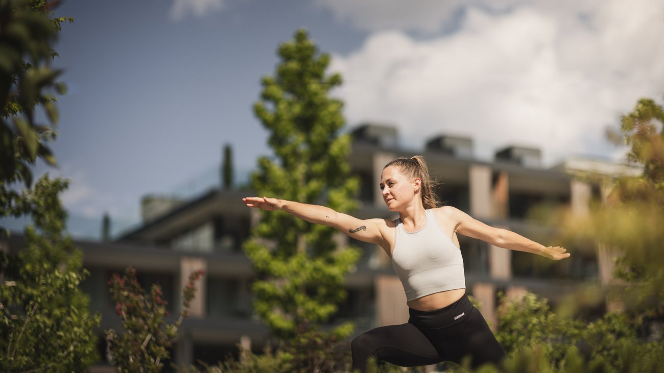 Frau macht Yoga-Pose im Freien mit modernen Gebäuden im Hintergrund