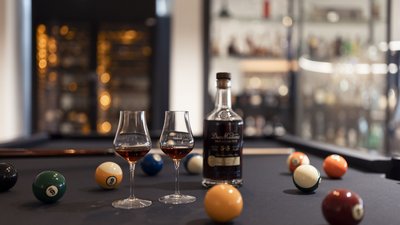 Due bicchieri e una bottiglia di rum su un tavolo da biliardo con palle