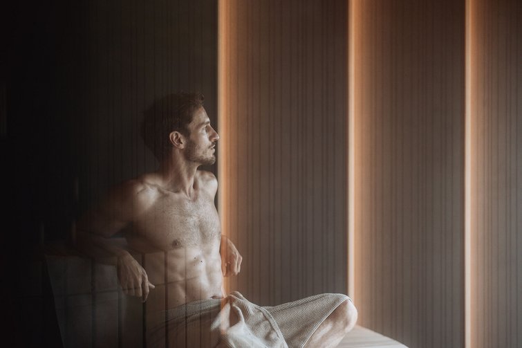 Die Heimat des Strahlens: Ihr Wellnesshotel in Südtirol Mann sitzt entspannt in Sauna mit Handtuch um die Taille