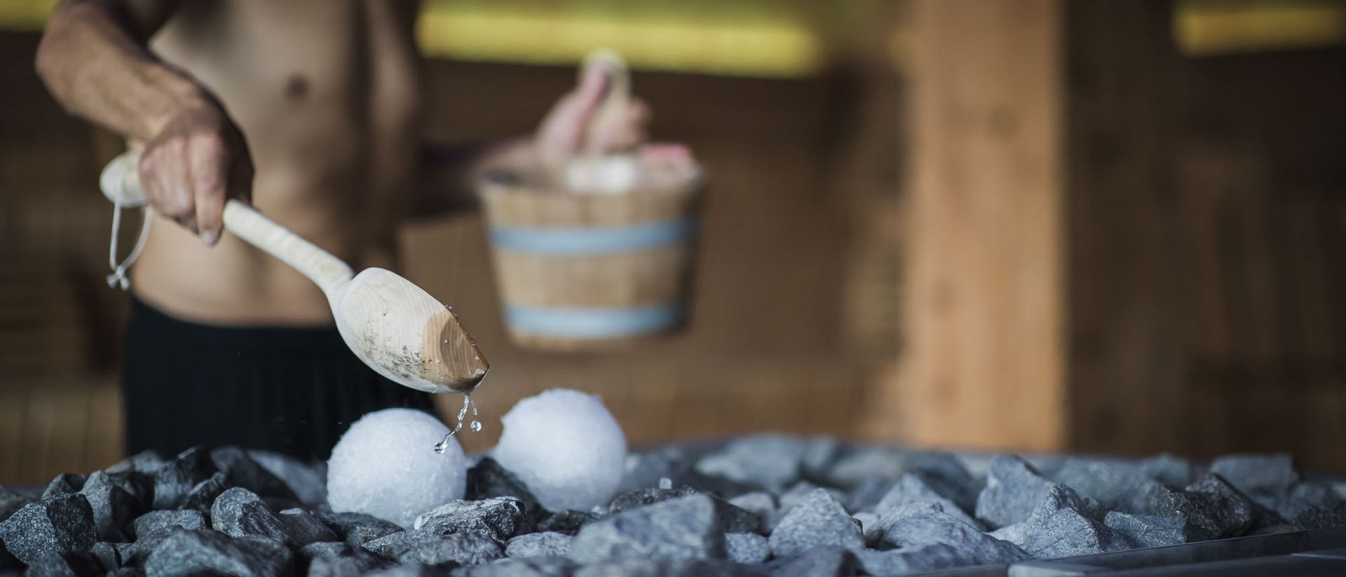 Man pouring water on hot stones in sauna