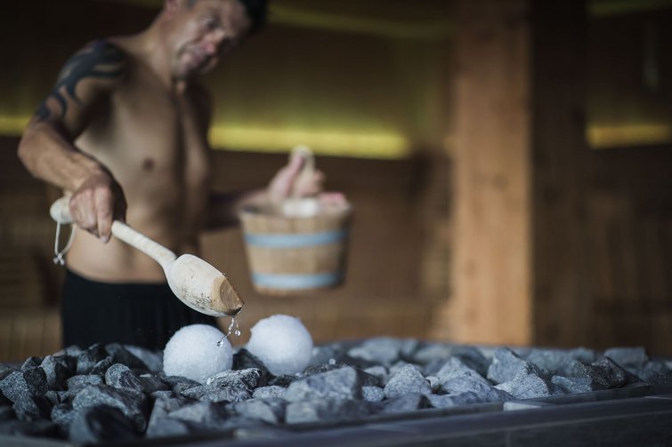 Uomo versa acqua sulle pietre calde nella sauna