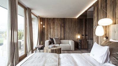 Camera d'hotel accogliente con pareti in legno, letto grande e divano vicino a grandi finestre