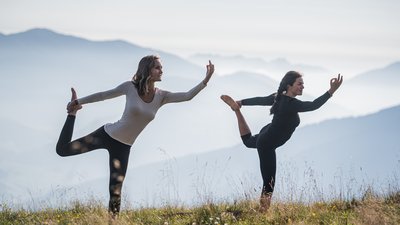 Due donne praticano yoga all'aperto in un paesaggio montano