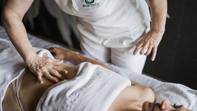 Therapeutin führt Bauchmassage bei liegender Frau durch