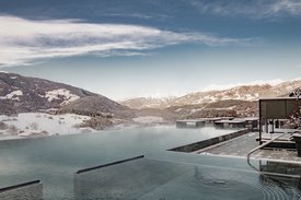 Eine regenerierende Auszeit vor Weihnachten Infinity-Pool mit Winterlandschaft und Bergen im Hintergrund