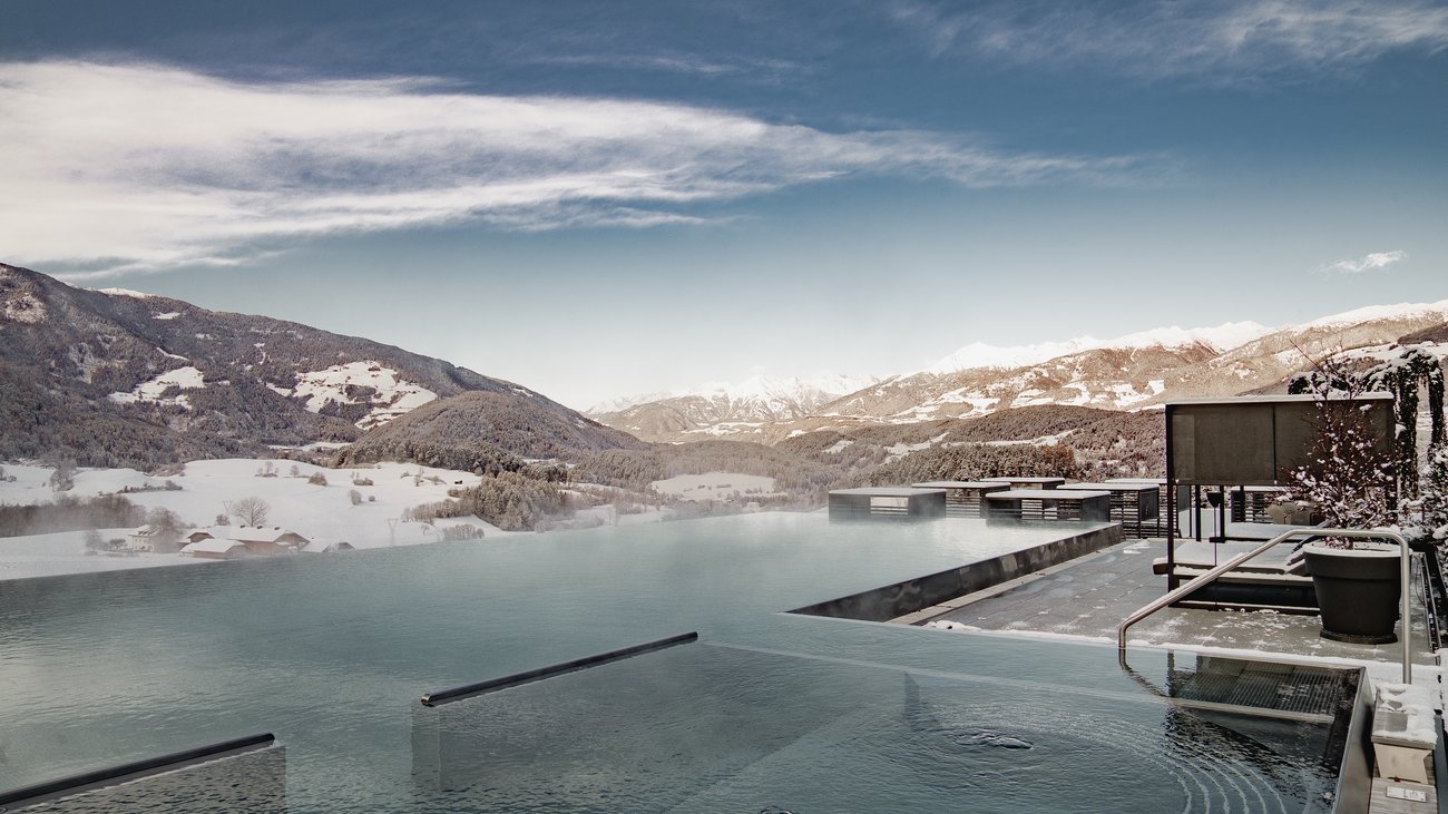 Infinity-Pool mit Winterlandschaft und Bergen im Hintergrund