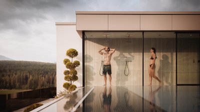 Photos from your hotel in Pfalzen in Val Pusteria/Pustertal People in swimwear under outdoor showers of a modern building by the pool