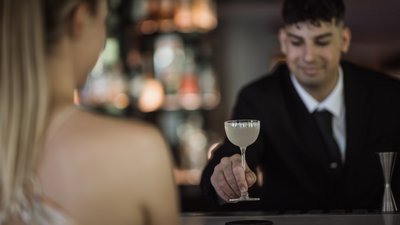 Barista serve un cocktail a una donna al bancone