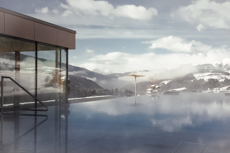 Beheizter Außenpool mit Blick auf schneebedeckte Berge und bewölkten Himmel