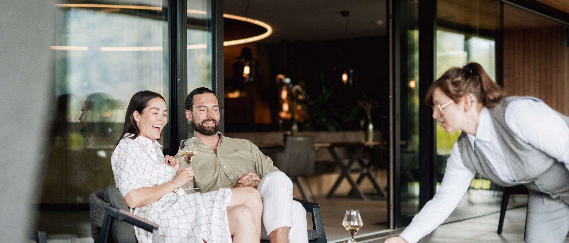 Couple sitting on terrace, waitress serving drinks and snacks