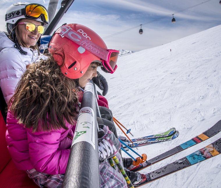 Due sciatori sulla seggiovia con sci e caschi in una giornata di sole