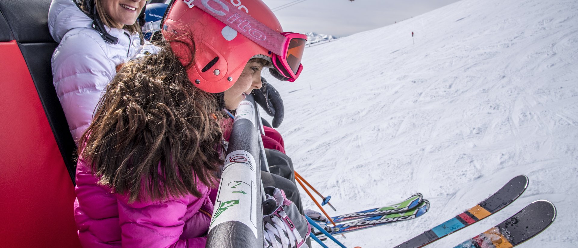 Due sciatori sulla seggiovia con sci e caschi in una giornata di sole