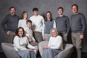 Ten smiling people in gray and white clothing against a gray background