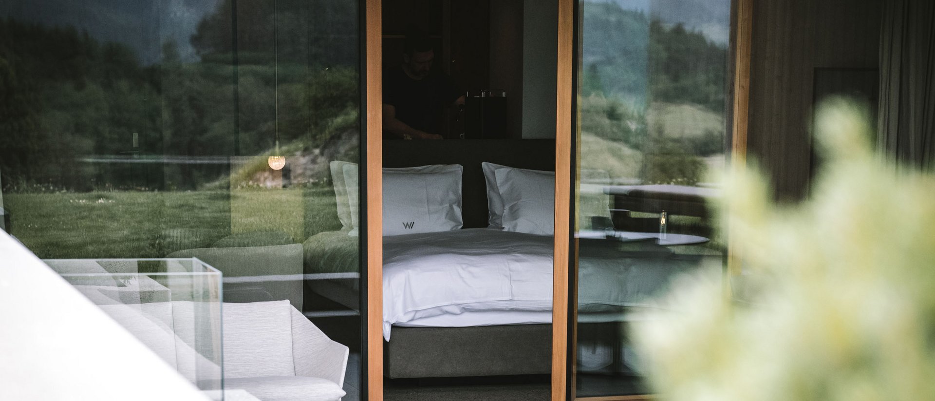 Your source of enrichment: our hotel at Mt Plan de Corones View through glass of modern hotel room with bed and mountain landscape