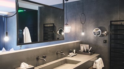L’esclusività in foto: il nostro chalet in Alto Adige di lusso Specchio bagno moderno sopra lavabo con parete grigia e asciugamano