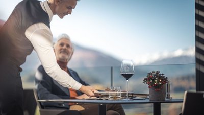 Cameriere serve un uomo anziano in un ristorante con vista sulle montagne