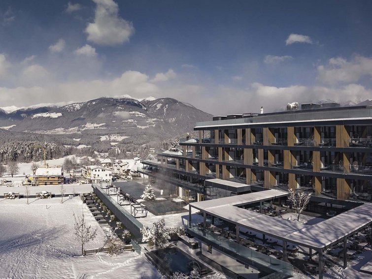 Modernes Hotel neben verschneiter Landschaft und Bergen im Winter