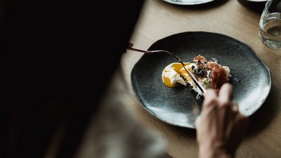 L’esclusività in foto: il nostro chalet in Alto Adige di lusso Persona che mangia piatto con uovo e prosciutto su piatto nero