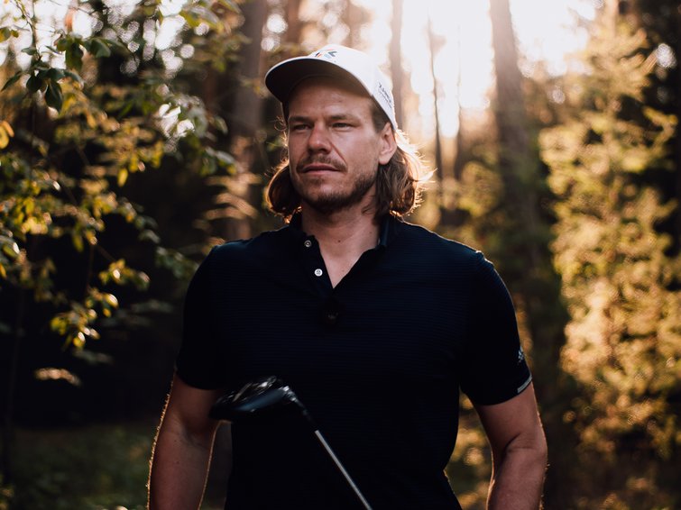 Platzreife in Südtirol erlangen: unser Premium-Golf-Service Mann mit Golfschläger und Kappe in einem sonnenbeschienenen Wald