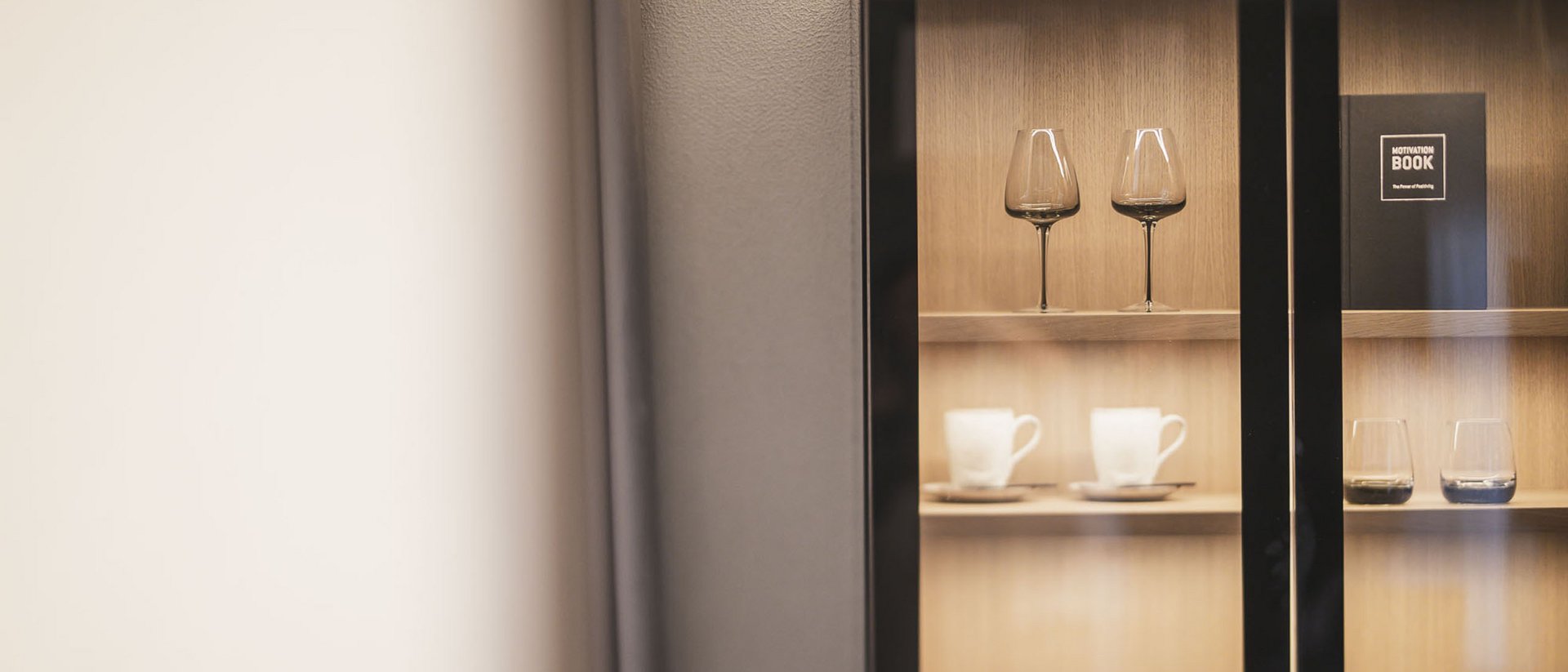 Glasvitrine mit Weingläsern, Tassen und einem Buch