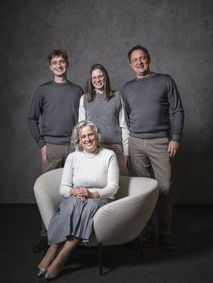 Four smiling people in gray and white clothing against a gray background