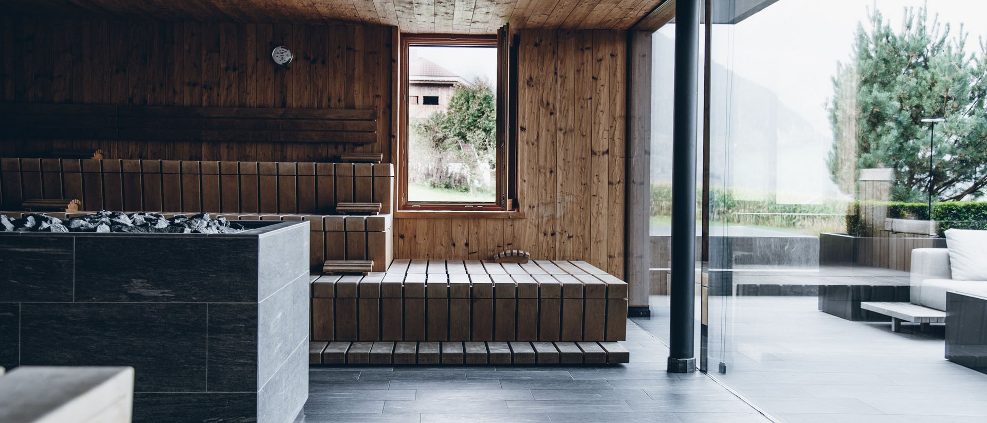Modern sauna room with wooden walls and glass windows overlooking garden
