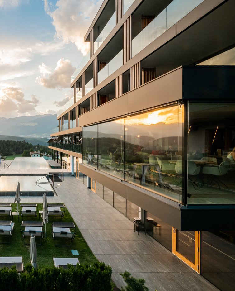 Moderner Hotelpool mit Liegestühlen bei Sonnenuntergang in einer Berglandschaft