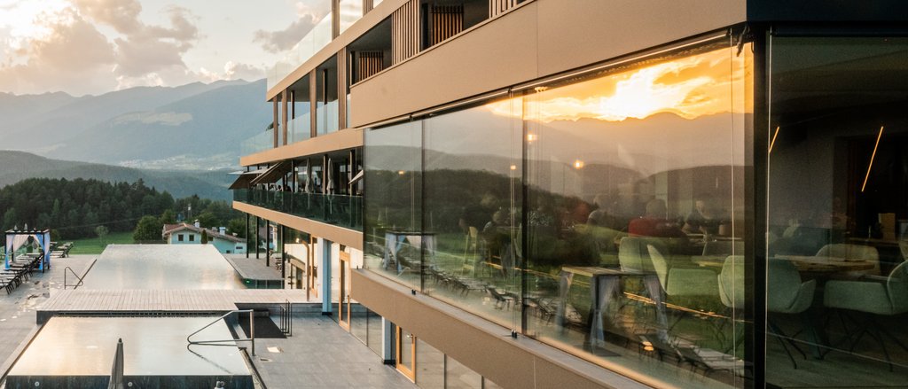 The multi-faceted Sonnenspa at our spa hotel in South Tyrol Modern hotel pool with sun loungers at sunset in a mountain landscape