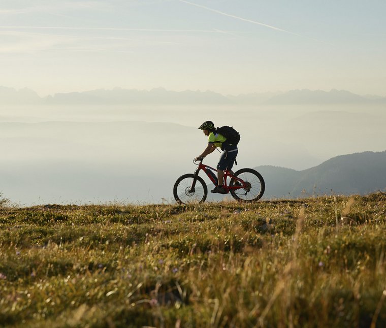 Ciclista su sentiero di montagna con paesaggio nebbioso sullo sfondo