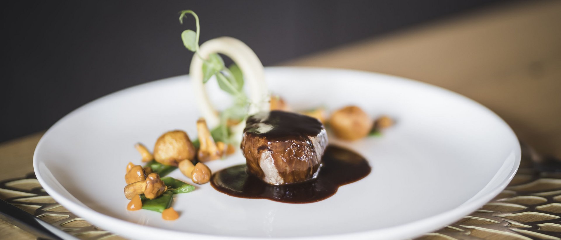 Filetto di manzo con salsa scura e funghi servito su piatto bianco