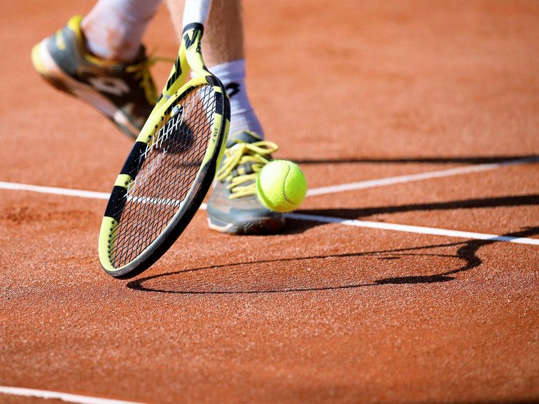 Tennis- & Padelurlaub in Südtirol: unser Premium-Service Tennisschläger und Ball auf einem Sandplatz