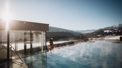 Photos from your hotel in Pfalzen in Val Pusteria/Pustertal Steaming outdoor pool with mountain view under clear sky and sunlight