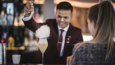 Barman spruzza liquido su un cocktail fumante al bancone