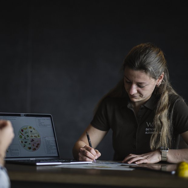 Consulenza nutrizionale con laptop e appunti scritti al tavolo