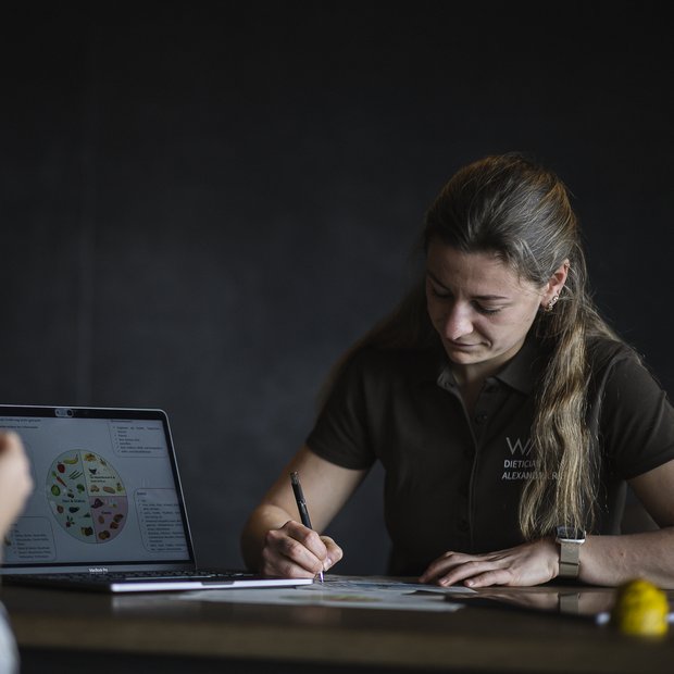 Nutrition consultation with laptop and handwritten notes on table
