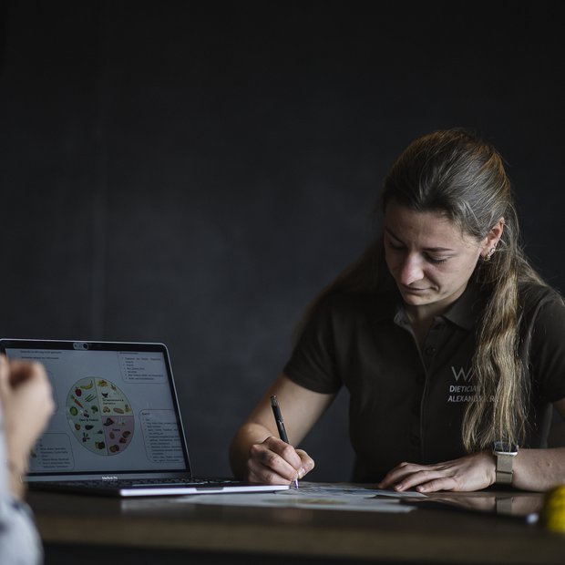 Ernährungsberatung mit Laptop und schriftlichen Notizen am Tisch