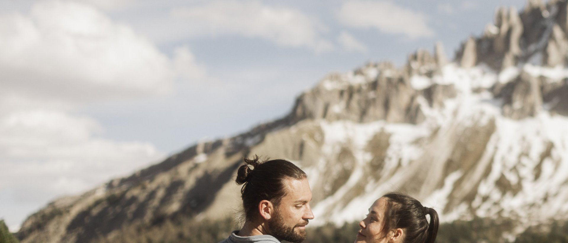 Außergewöhnliche Erlebnisse, Reiten und Yoga im Urlaub Paar wandert vor verschneiten Bergen und grünen Wäldern bei klarem Himmel