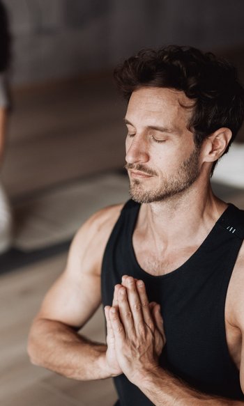 Man and woman meditating together with closed eyes and hands in prayer