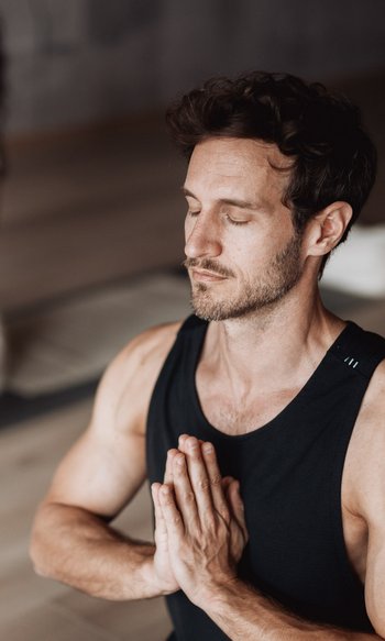 Mann und Frau meditieren zusammen mit geschlossenen Augen und gefalteten Händen