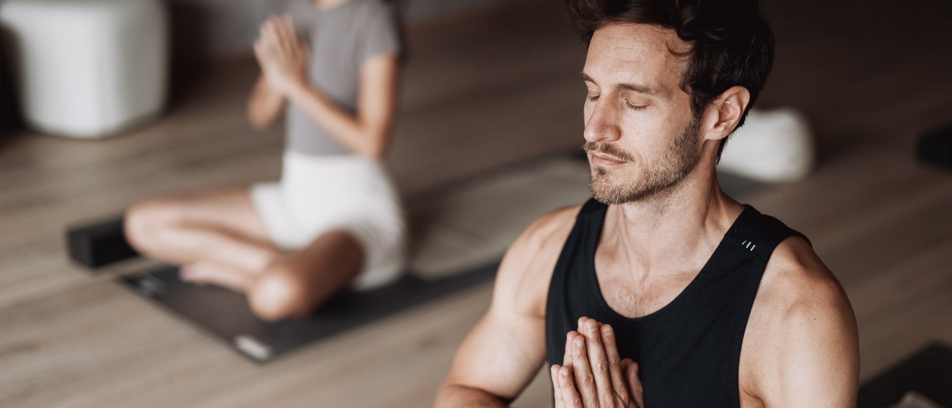 Man and woman meditating together with closed eyes and hands in prayer