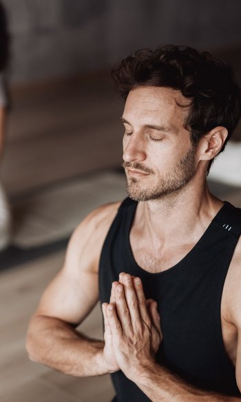 Uomo e donna meditano insieme con occhi chiusi e mani giunte