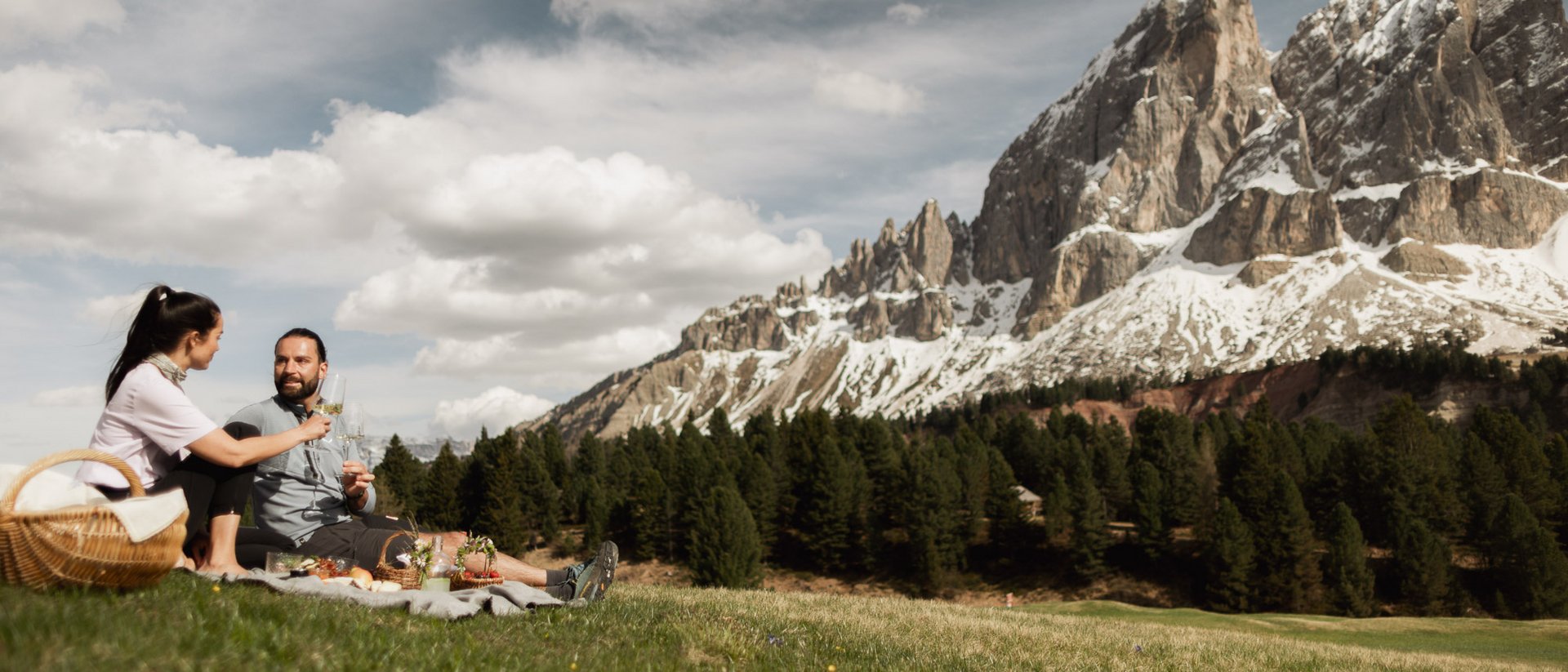 Coppia fa picnic con vista sulle montagne innevate e foresta