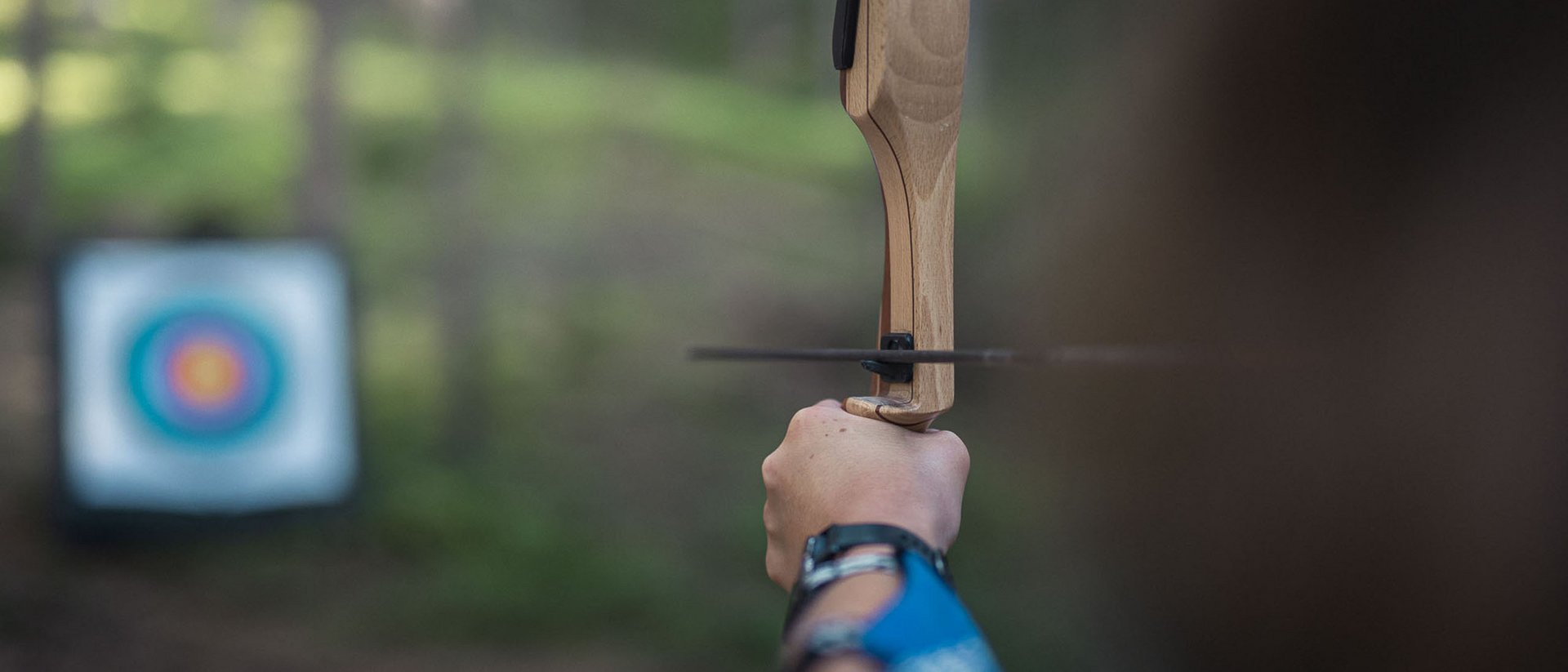 Persona mira con un arco verso un bersaglio all'aperto