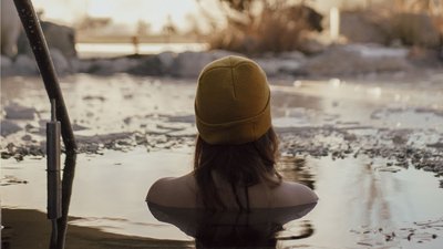 Photos from your hotel in Pfalzen in Val Pusteria/Pustertal Woman wearing yellow beanie sitting in cold water surrounded by ice
