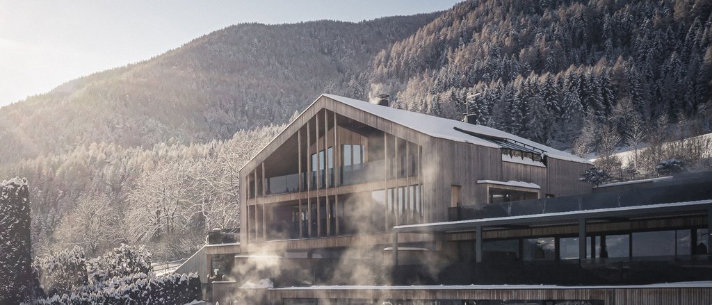 Der facettenreiche Spa unseres Spa-Hotels in Südtirol Modernes Holzhaus mit Schnee und Nebel vor bewaldetem Berg