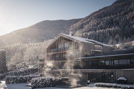 Eine regenerierende Auszeit vor Weihnachten Modernes Holzhaus mit Schnee und Nebel vor bewaldetem Berg